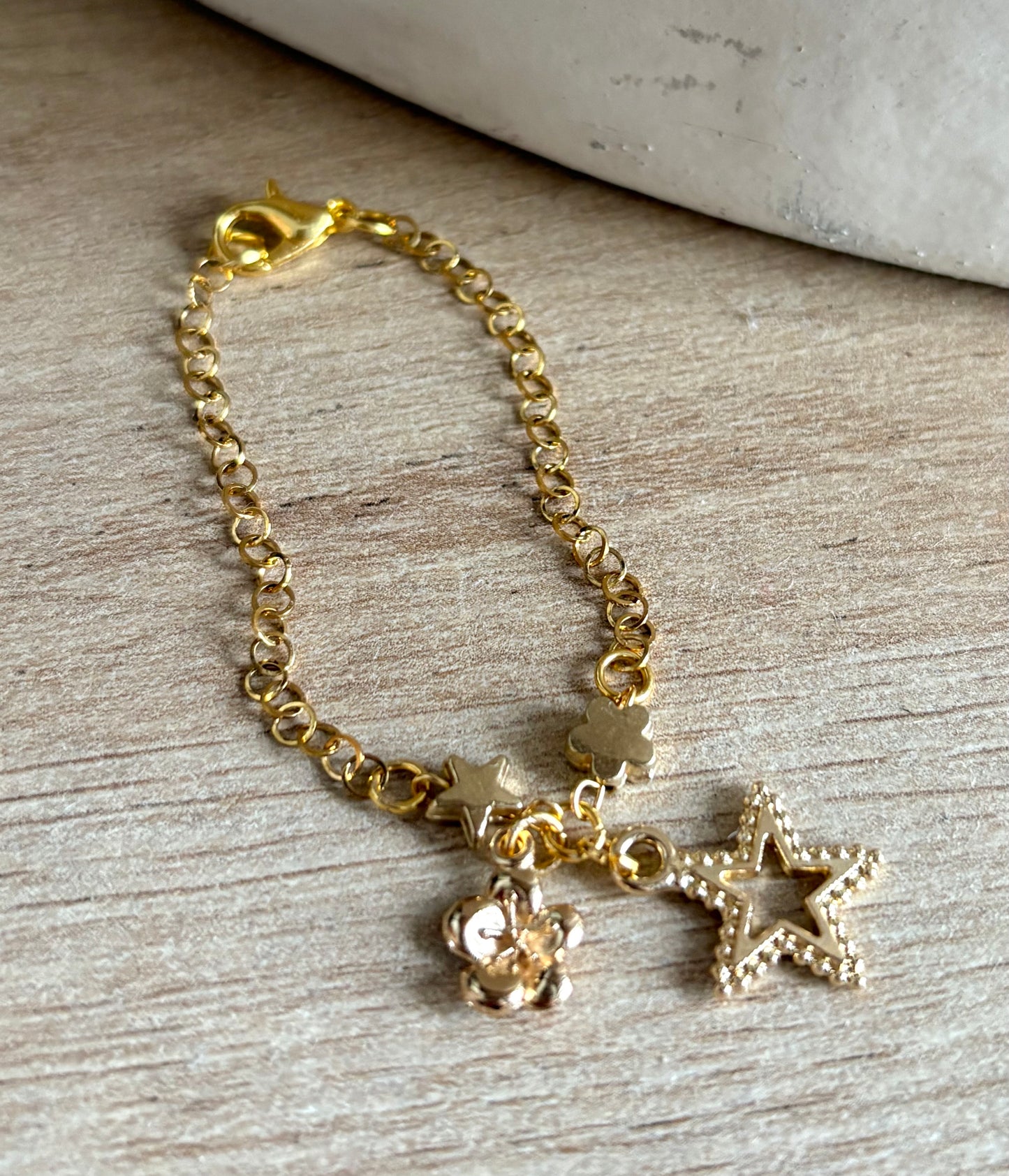 Pulsera de Niña Hecha a Mano en Acero Inoxidable con Baño de Oro y Dijes de Flor, Estrella y Corona – 13 cm