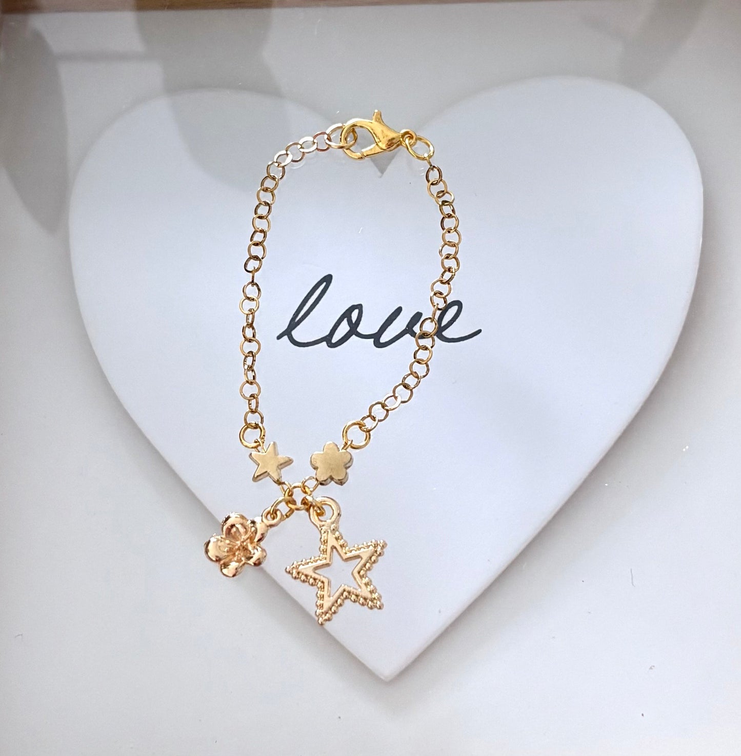 Pulsera de Niña Hecha a Mano en Acero Inoxidable con Baño de Oro y Dijes de Flor, Estrella y Corona – 13 cm